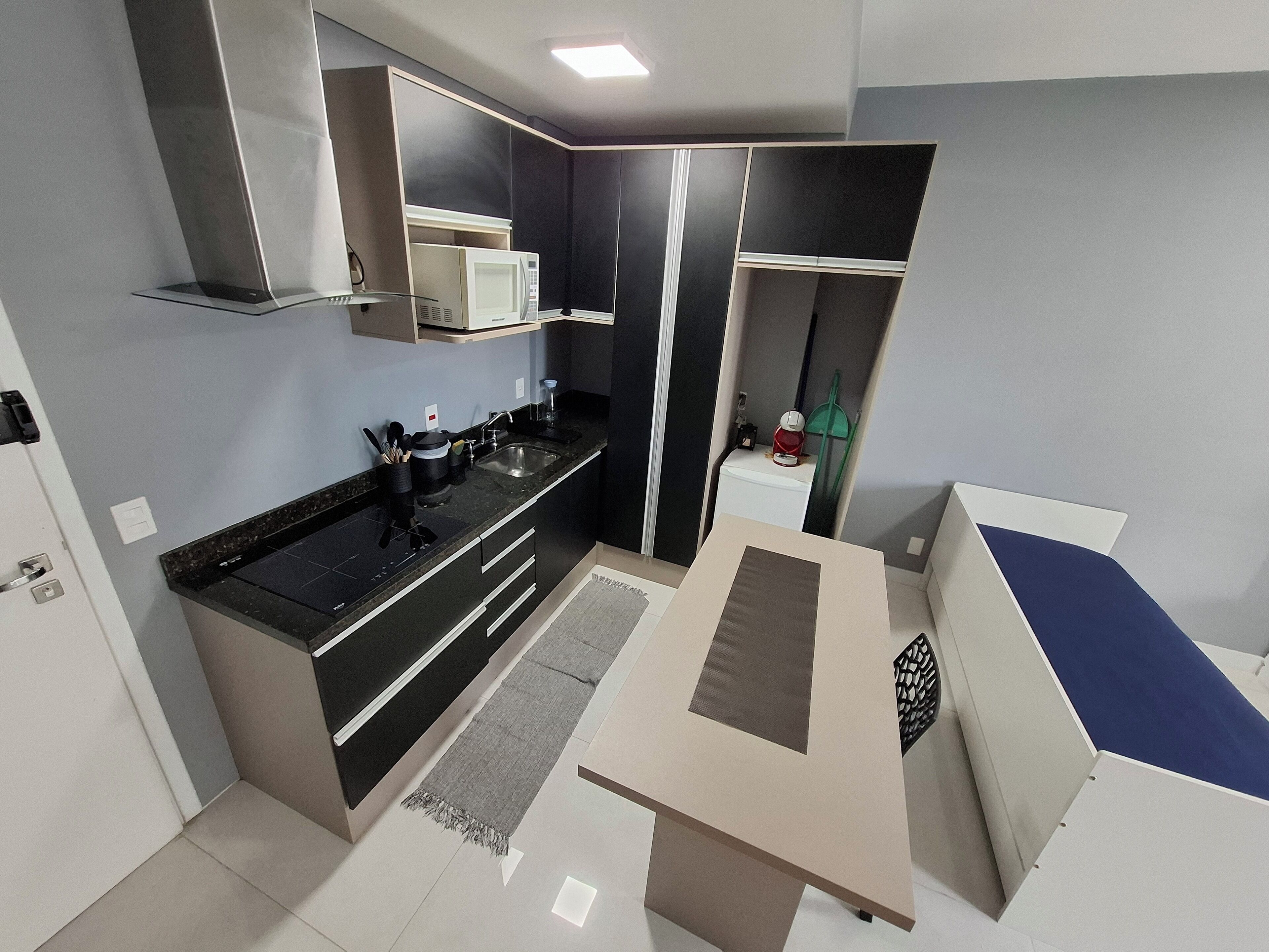 A compact kitchen with a microwave, sink, and modern cabinetry.