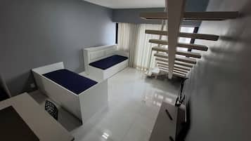Quarto moderno com duas camas, uma escrivaninha e um arranhador para gatos.