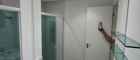 A modern bathroom with a glass shower enclosure, a marble sink, and a large mirror.