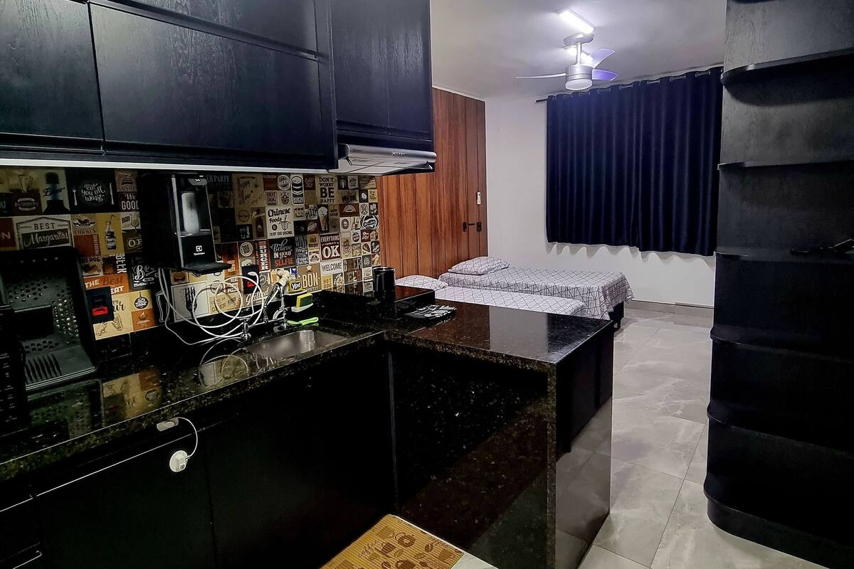 Une cuisine moderne avec des meubles noirs, un îlot central et un tapis décoré sur le thème du café.