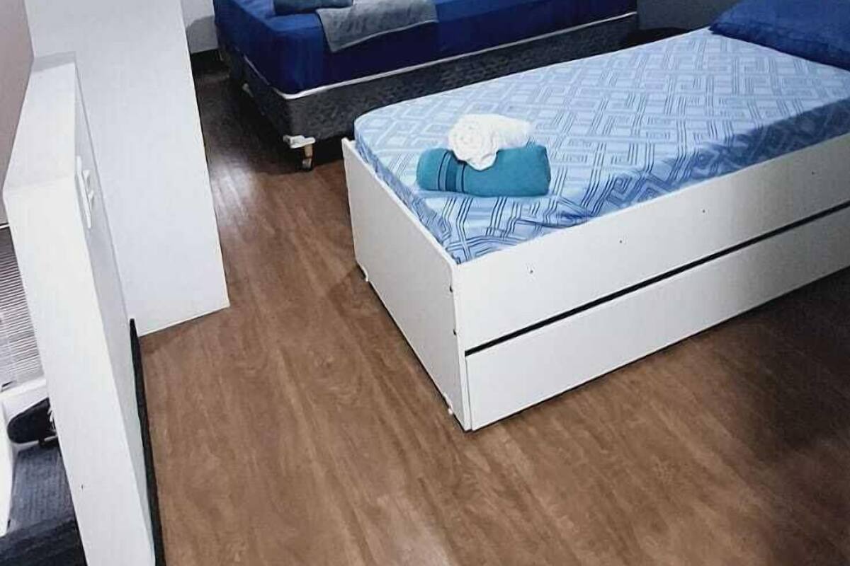 Une chambre moderne avec deux lits, un ventilateur de plafond et une armoire.