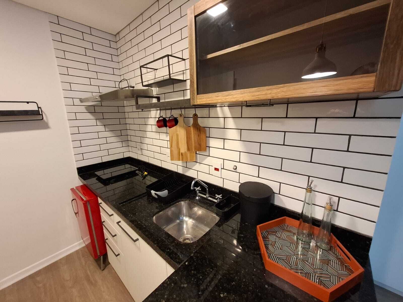 Una cocina moderna con azulejos tipo metro blancos, encimeras negras y armarios de madera.