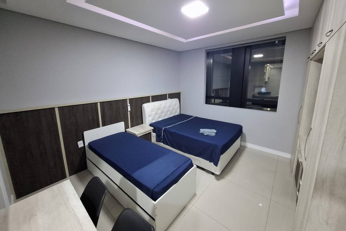 Une chambre d’hôtel moderne avec deux lits, un bureau et une fenêtre.