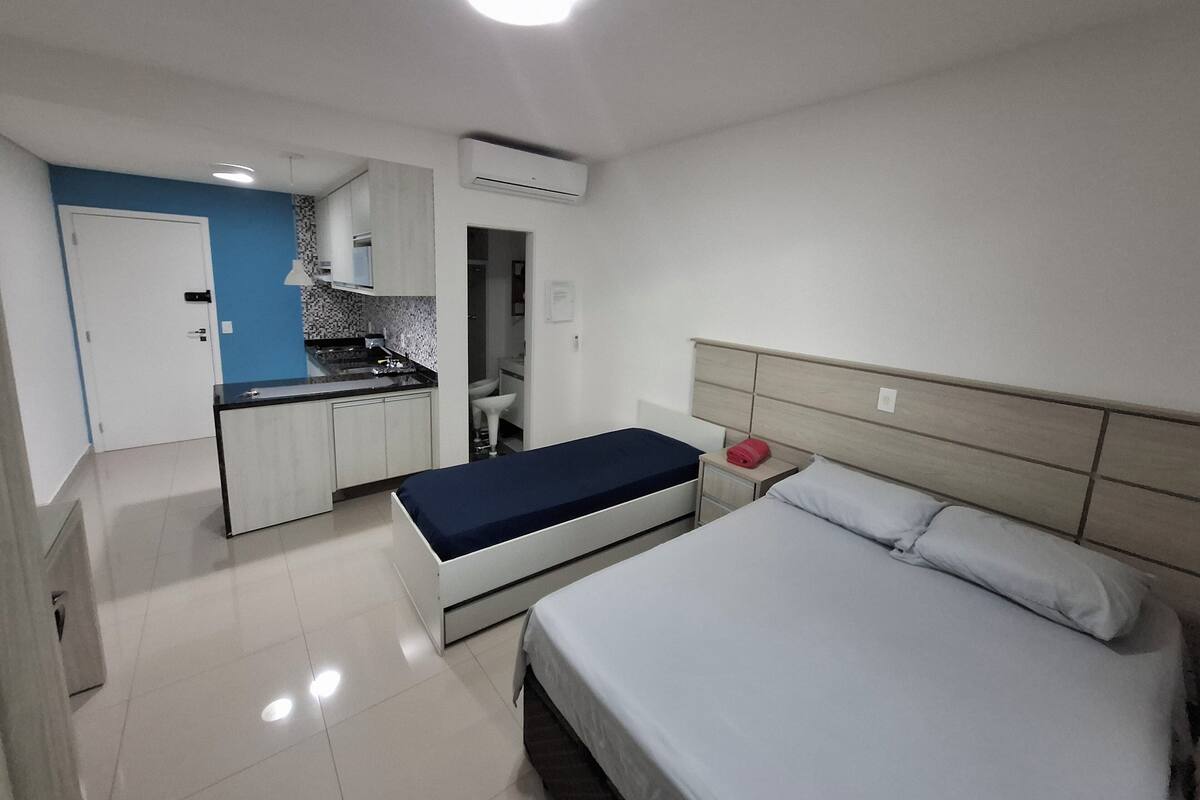 Une chambre d’hôtel de taille réduite, comprenant un lit, une table de chevet et un petit coin cuisine.