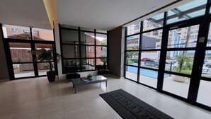 A modern hotel lobby with large windows, a reception desk, and a potted plant. - Edificio Selenita Loft e Duplex (Barueri)