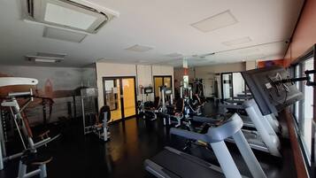 Ein Fitnessstudio mit Laufbändern, Kraftgeräten und einer Spiegelwand.