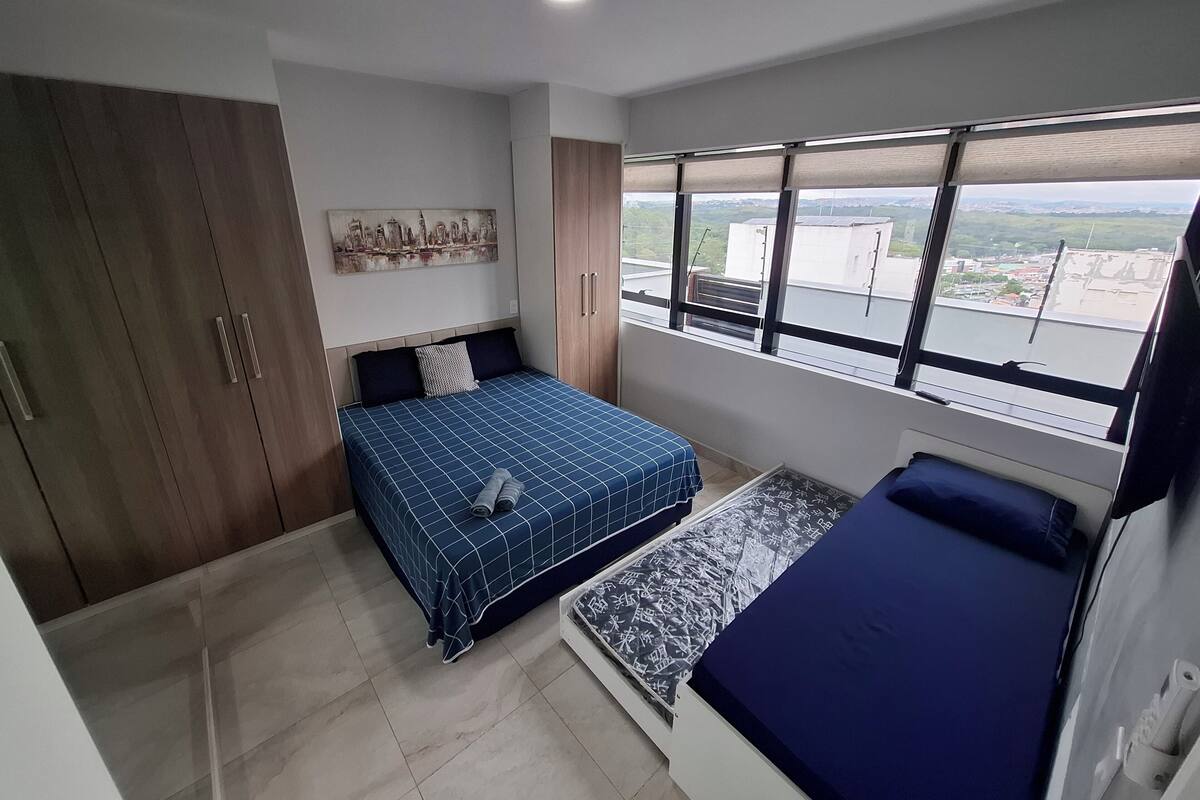 Une chambre à coucher avec un lit, une fenêtre donnant sur un beau paysage et une armoire.