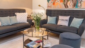 A modern living room with two grey sofas, a glass coffee table, and a decorative vase with flowers. - Livingroom Mathildenhöhe (Darmstadt)