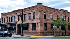 A brick building with a green awning, a sign reading "HILL," and a street lamp. - Charming and Beautiful Downtown Whitefish Condo in Historic Building (Whitefish)