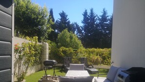 A backyard with a barbecue grill, outdoor seating, and a water tank. - Villa Contemporaine (Lattes)