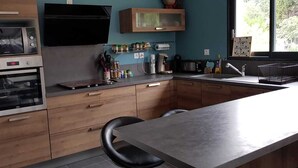 A modern kitchen with a built-in oven, microwave, and a large window providing natural light. - Villa Contemporaine (Lattes)