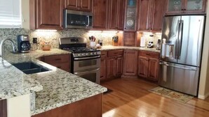 A kitchen with wooden cabinets, a stainless steel refrigerator, a microwave, a stove, and granite countertops. - Spacious home located near Mtns & Downtown Denver! (Westminster)