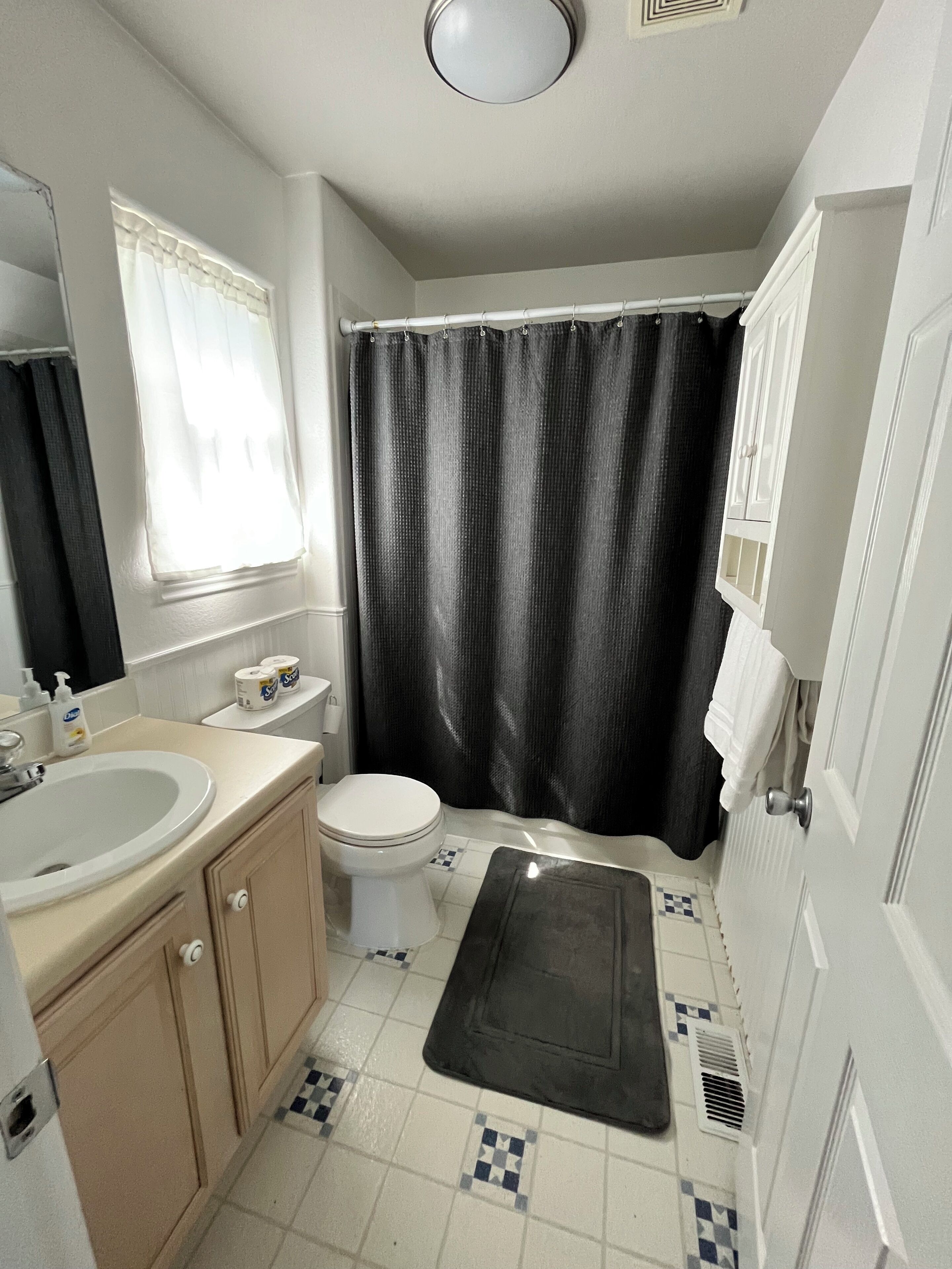 A bathroom with a toilet, sink, and shower curtain.