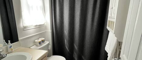 A bathroom with a toilet, sink, and shower curtain.