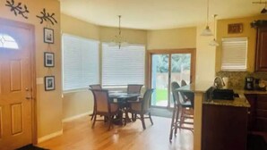 A spacious kitchen with a dining area, wooden flooring, and a large window providing natural light. - Spacious home located near Mtns & Downtown Denver! (Westminster)