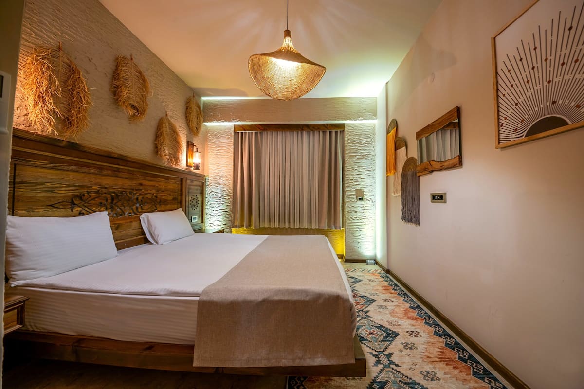 A hotel room with a large bed, a hanging light fixture, and a patterned carpet.