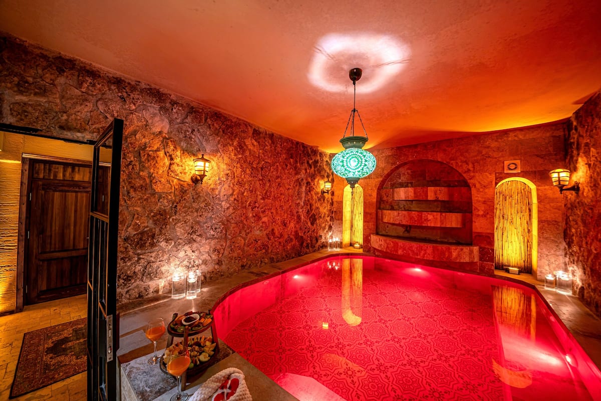 A spa area with a red heated pool, stone walls, and traditional lighting fixtures.