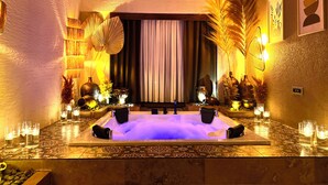 A spa room with a large bathtub, decorative plants, and candles.