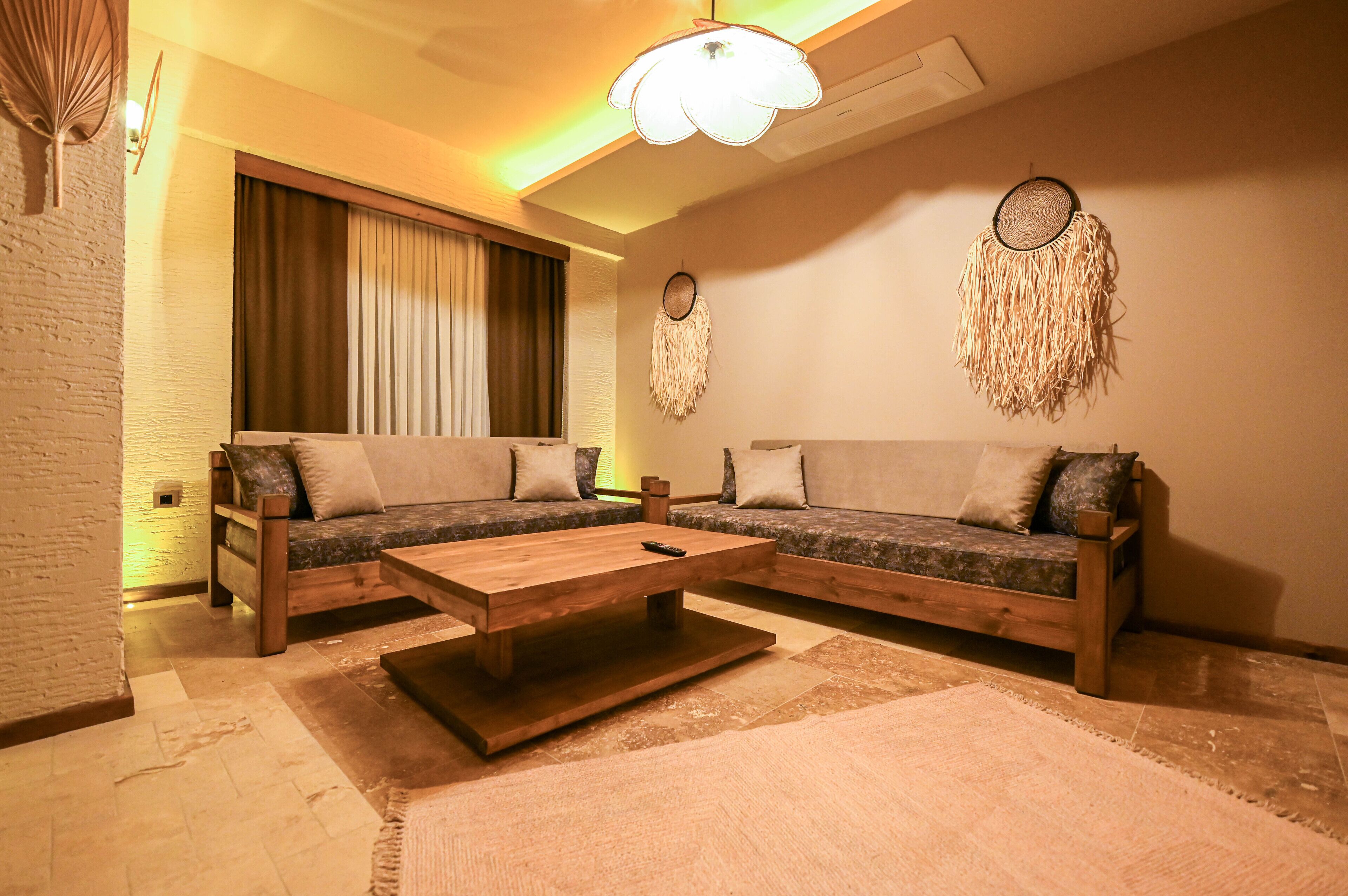 A cozy living room with two sofas, a wooden coffee table, and a large window with curtains.