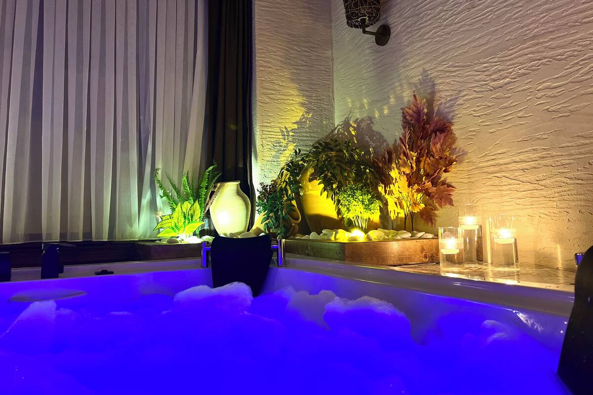 A spa area with a hot tub, plants, and candles.