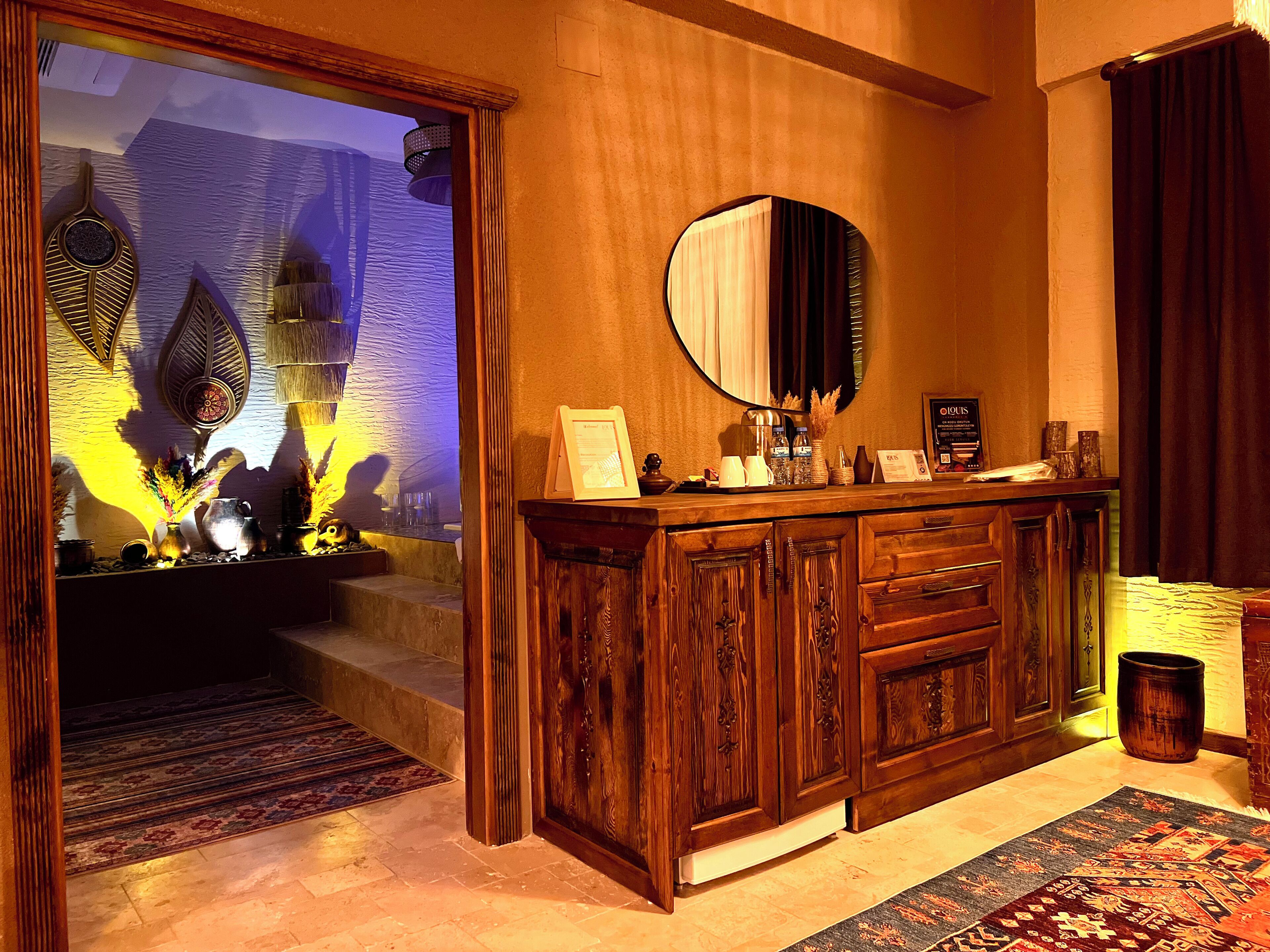 A hotel lobby with a wooden reception desk, a large mirror, and a decorative wall with a textured pattern.