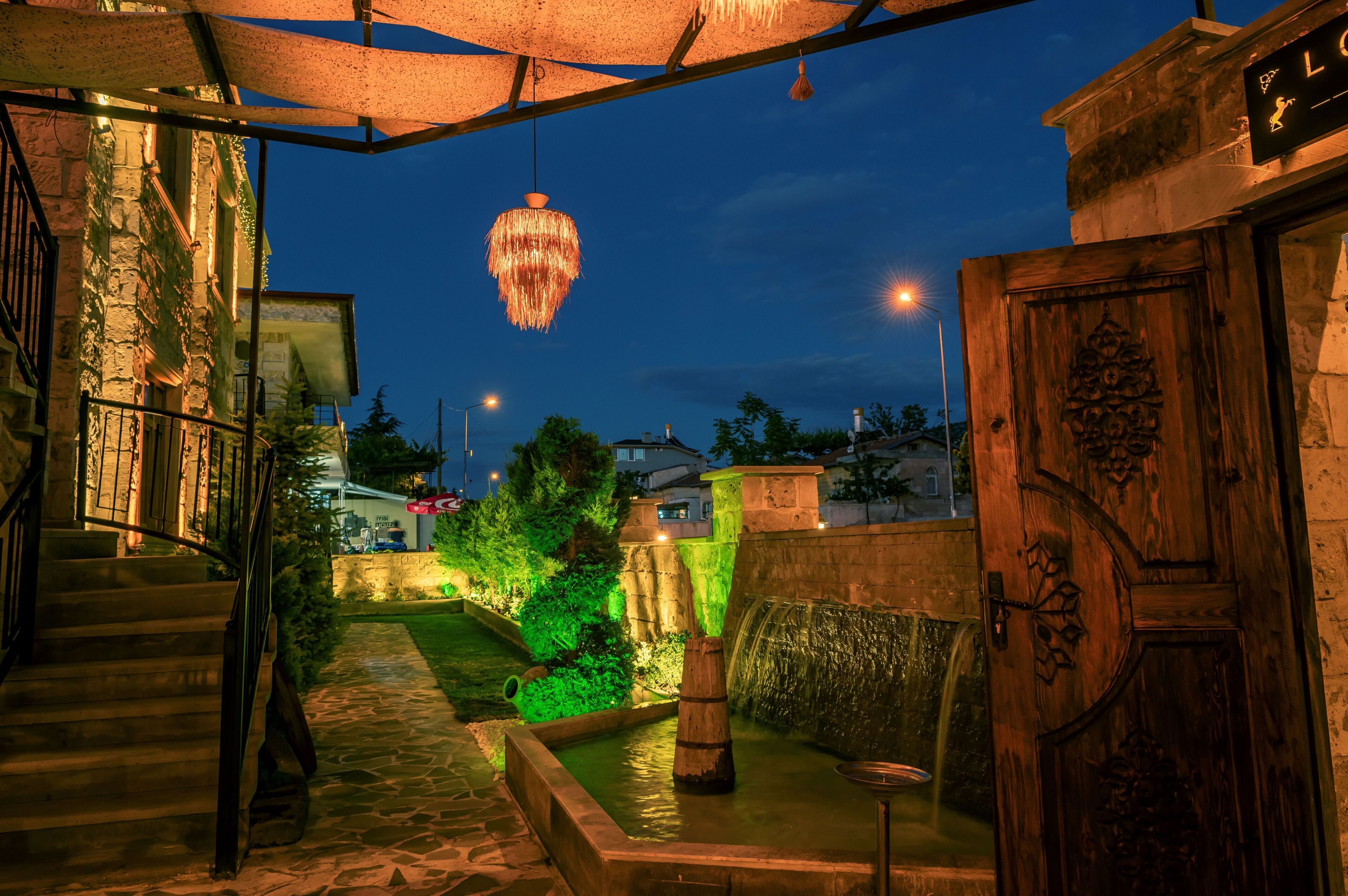 A stone staircase leading to a wooden door, a hanging light fixture, and a small water feature.