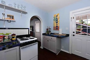 A kitchen with white cabinets, a stove, and a countertop with various items. There is a door with a window and a sign that says "FLORIDA".