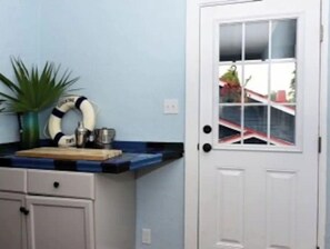 A kitchen with a blue countertop, a white cabinet, and a door with a window.