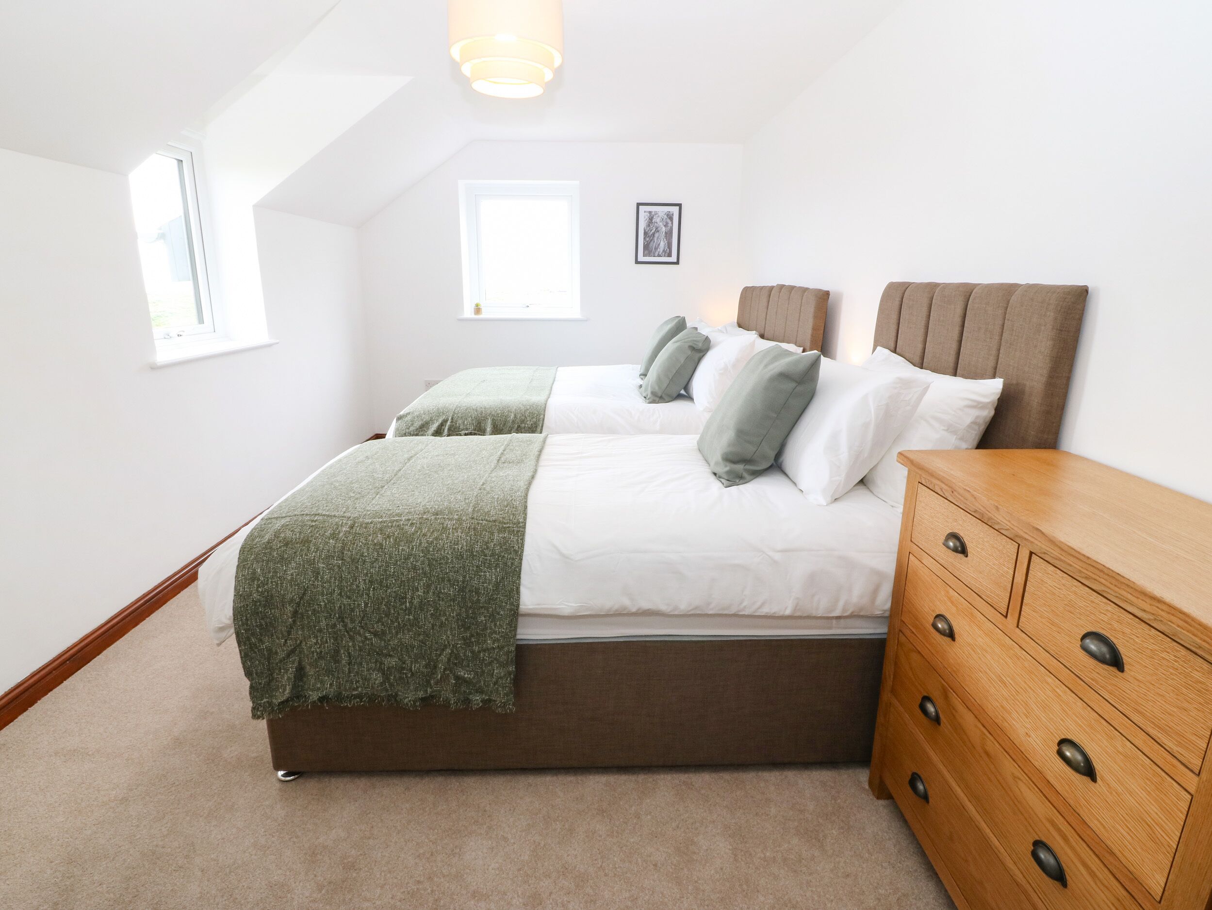 A bedroom with a bed, a wooden dresser, and a window.