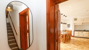 A hallway with a wooden door, a mirror, and a staircase. - Bryn Meilw (Holyhead)