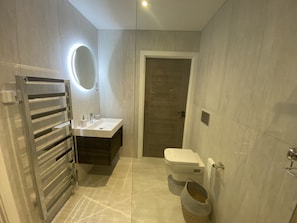 A modern bathroom with a built-in sink, a toilet, and a towel rack.