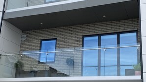 A multi-story building with a brick facade, large windows, and a glass balcony railing. - Stunning Cliff Edge Apartment in Newquay (Newquay)
