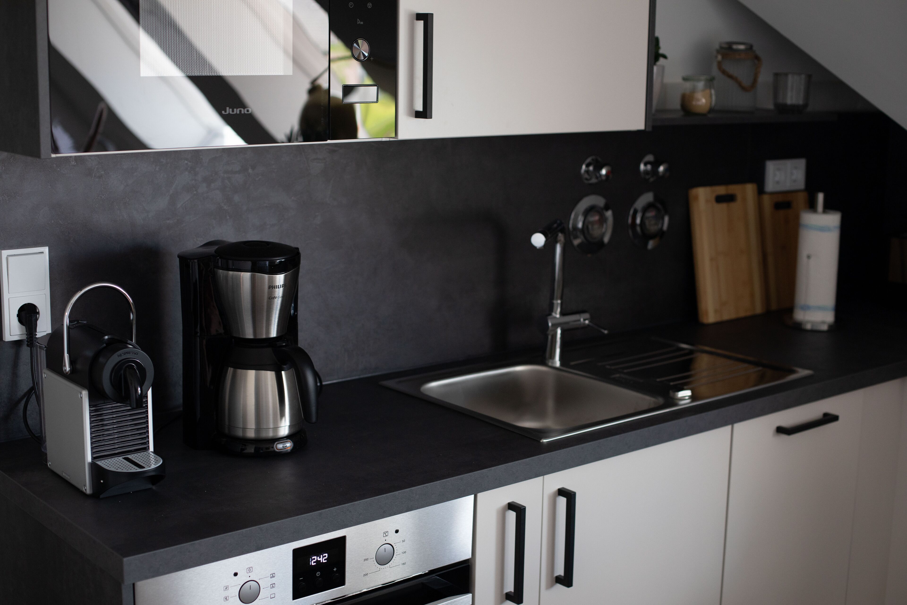 Ett modernt kök med en kaffebryggare, en espressomaskin och en digital klocka.