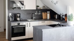 Una cocina moderna con horno empotrado, cafetera y lavaplatos.