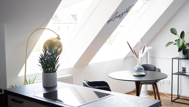 Una habitación moderna y luminosa con tragaluz, una mesa redonda y una planta en maceta.