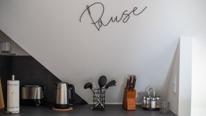 Una cocina con un cartel que dice 'Pause', una tetera, un tostador, un bloque de cuchillos y varios utensilios de cocina.