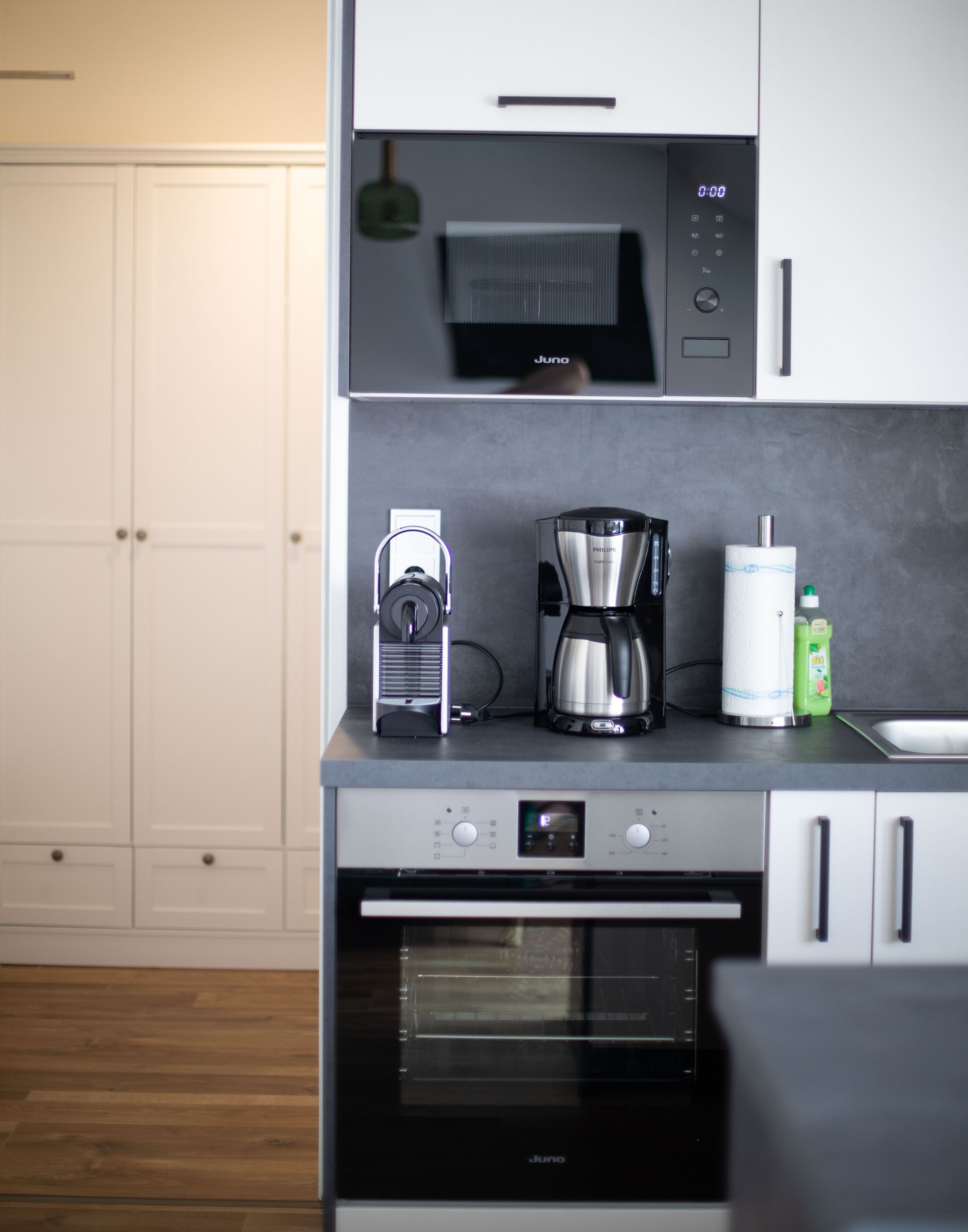 A modern kitchen with a built-in microwave, coffee maker, and a small refrigerator.