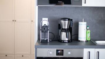 A modern kitchen with a built-in microwave, coffee maker, and a small refrigerator.