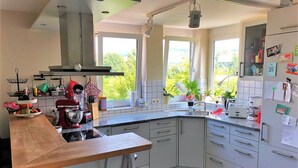 Een moderne keuken met een houten aanrecht, roestvrijstalen apparatuur en een groot raam met uitzicht op groen.