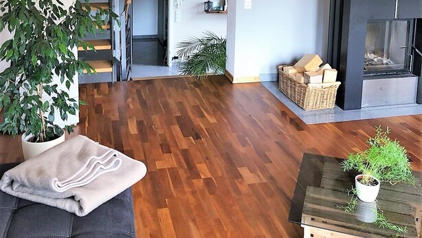 Een ruime woonkamer met een houten trap, een open haard en een boekenkast.