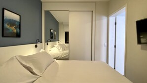 Ein Hotelzimmer mit Bett, Spiegel und Fernseher an der Wand.