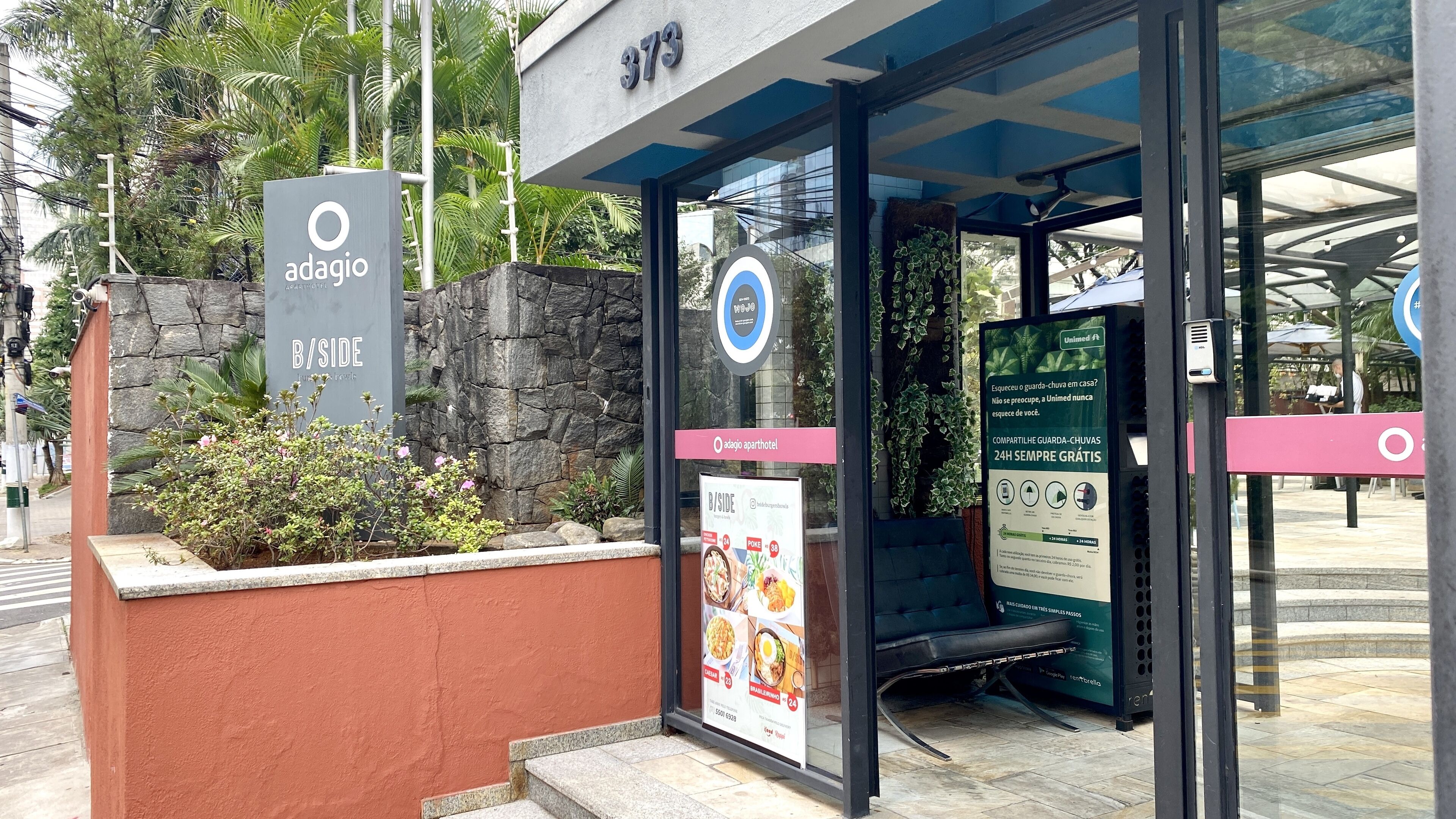 A hotel entrance with a stone facade, a glass door, and a sign for 'adagio B/Side'.