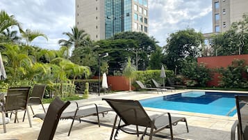 A swimming pool with lounge chairs and palm trees.