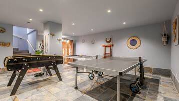Une pièce équipée d’une table de ping-pong, d’un baby-foot et d’un escalier menant à un autre niveau.