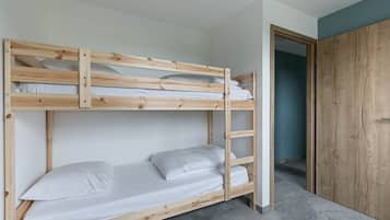Een stapelbed met witte beddengoed, een houten trap en een garderobe in de aangrenzende kamer.