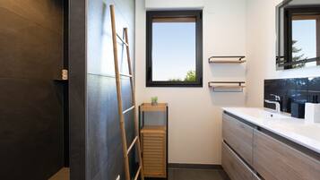 A modern bathroom with dark wooden walls, a large window, and a wooden ladder.