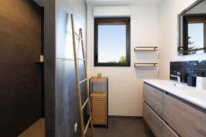 Ein modernes Badezimmer mit dunklen Holzvertäfelungen, einem großen Fenster und einer Holzleiter.