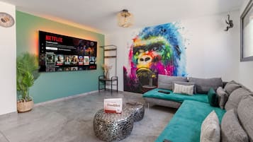 Een moderne woonkamer met een Netflix-scherm, een kleurrijk abstract schilderij en een gezellige zithoek.