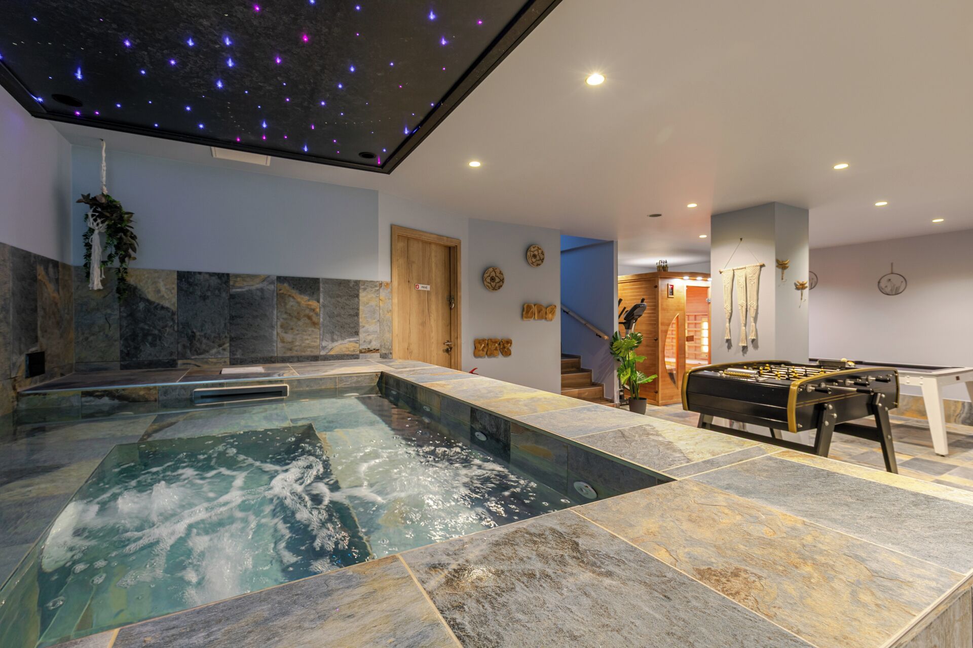 A spa area with a hot tub, a foosball table, and a ceiling with star projections.