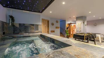 A spa area with a hot tub, a foosball table, and a ceiling with star projections.